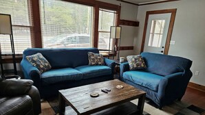 A living room with a blue sofa set, a wooden coffee table, and a checkered rug. - Dog Friendly, located Between Lake Placid and Saranac Lake with pontoon rentals (Ray Brook)