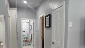 A hallway with wooden flooring, white doors, and a vase on the right. - Family-friendly stand alone apartment in a peaceful Suburb . (Burleson)
