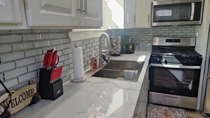 A modern kitchen with white cabinets, a stainless steel microwave, a double oven, and a marble countertop. - Family-friendly stand alone apartment in a peaceful Suburb . (Burleson)