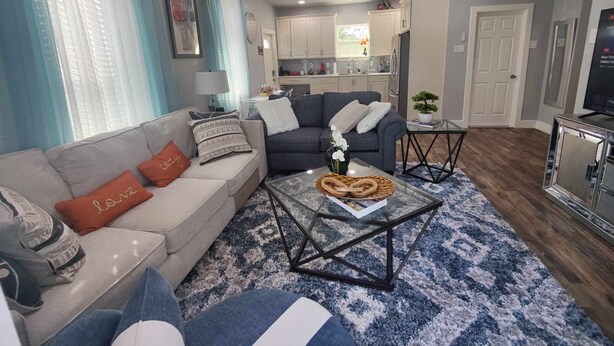 A living room with a sofa, coffee table, and a kitchen in the background. - Family-friendly stand alone apartment in a peaceful Suburb . (Burleson)