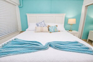 A bed with a white headboard, a blue and white patterned blanket, and decorative pillows.