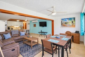 Ein Wohnzimmer mit einem braunen Sofa, einem Holztisch und einem Essbereich mit Tisch und Stühlen.