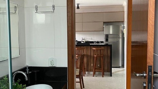 A modern kitchen with a central island, stainless steel appliances, and wooden cabinets. - Apto Maravilhoso com Vista Para o Mar, 50mts da Orla da Praia Grande em Ubatuba (Praia Grande Ubatuba)