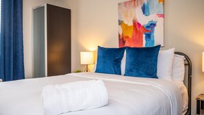 A hotel room with a large bed, a colorful abstract painting on the wall, and a nightstand with a lamp. - Downtown 2BR King Bed FREE Parking 1413 (Atlanta)