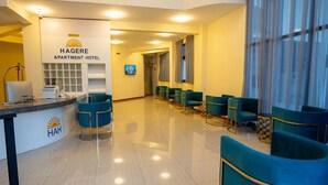 Un área de recepción con mostrador, sillas azules y un cartel para Hagere Apartment Hotel.