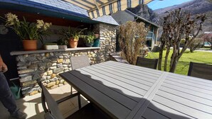 En udendørs patio med stenvæg, træbord og stole.