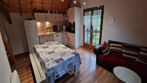 A cozy kitchen with wooden cabinets, a dining table with a patterned tablecloth, and a red sofa with striped cushions.