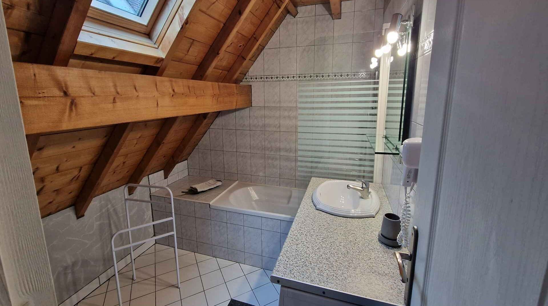 Ein modernes Badezimmer mit Holzboden, einer Badewanne, einem Waschbecken und einer Duschkabine aus Glas.