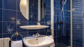 Un baño con lavamanos blanco, espejo y ducha.