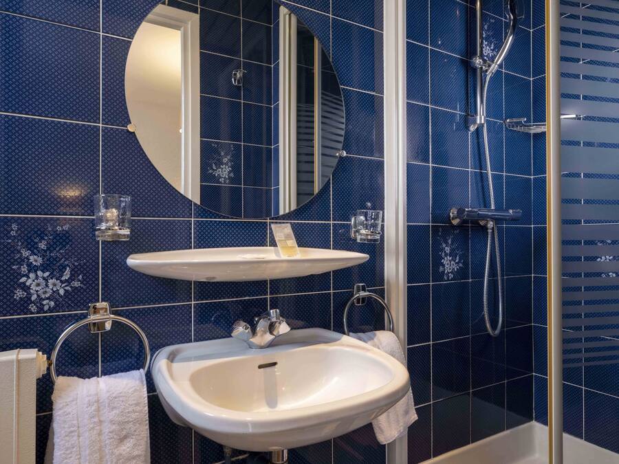 Un baño con lavamanos blanco, espejo y ducha.