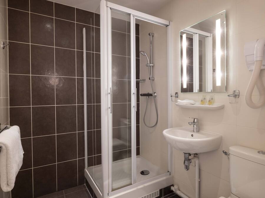 Un baño moderno con ducha de vidrio, lavamanos y retrete.