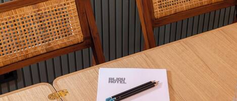 A wooden table with a white sheet of paper labeled "BIJU HOTEL" and two pencils.