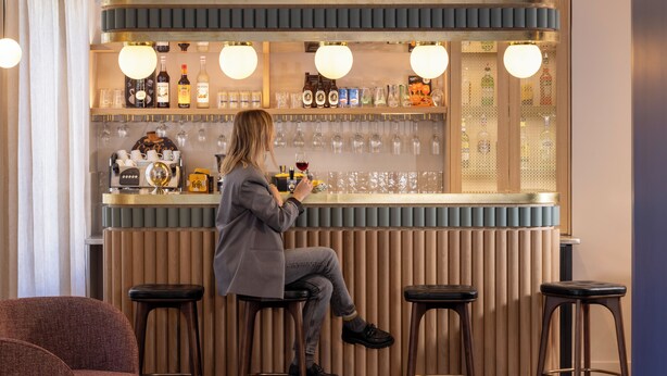 Un espace bar avec des tabourets, un comptoir et une variété de bouteilles et de verres.