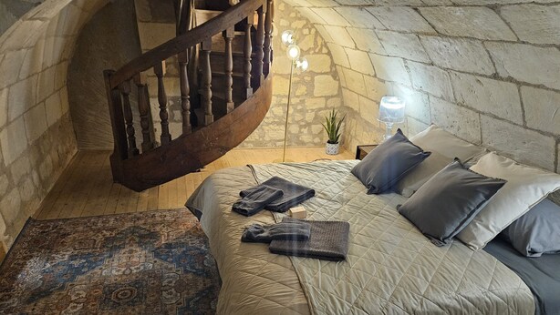 Ein Schlafzimmer mit einem Bett, einer Holztreppe, einer Lampe und einem Teppich.