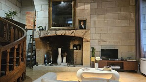 Ein Wohnzimmer mit Kamin, einer Couch, einem Fernseher und einer Treppe.