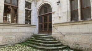 Ein Gebäude mit einer Stein-Fassade, einer Treppe aus Stein, die zu einer Glastür führt, und einer Wandlaterne.