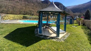 En lusthus med en pool och berg i bakgrunden.