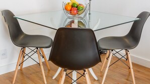 A dining area with a glass table, black chairs, and a fruit bowl. - Apartamento aconchegante na Praça Pôr do Sol (São Paulo)