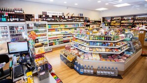 A grocery store with a variety of products, including a refrigerated section, shelves stocked with beverages, and a promotional sign. - Apartamento aconchegante na Praça Pôr do Sol (São Paulo)