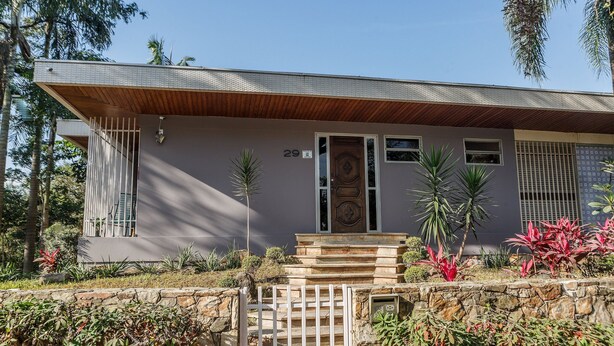 A modern house with a stone staircase leading to a wooden door, surrounded by tropical plants. - Apartamento aconchegante na Praça Pôr do Sol (São Paulo)
