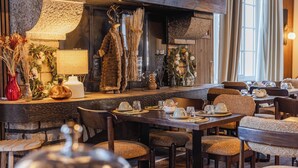 A restaurant with wooden furniture, a fireplace, and various decorative items. - Le Chalet d'Antoine (Megeve)