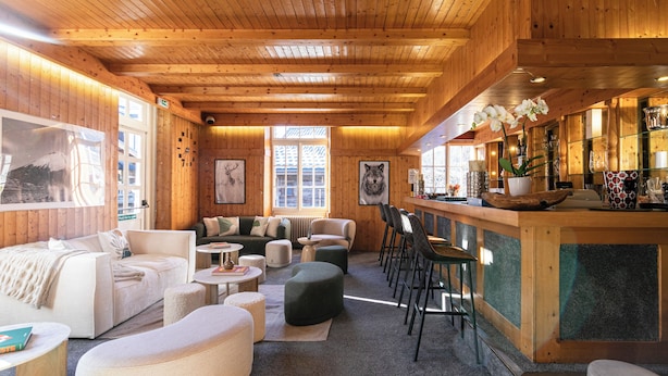 A cozy, wood-paneled interior with a bar area, seating arrangements, and artwork on the walls. - Le Chalet d'Antoine (Megeve)