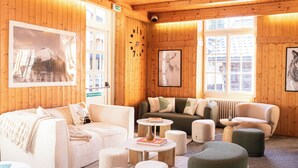 A cozy wooden interior with a sofa, two armchairs, a coffee table, and ottomans. - Le Chalet d'Antoine (Megeve)