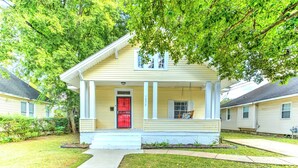 A two-story house with a red door, white columns, and a covered porch. - Updated Midtown Bungalow • Walk to Cooper-Young Dining • Sleeps 7 • Close to All (Memphis)