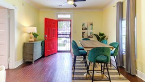 A dining area with a wooden table, green chairs, a red door, and a ceiling fan. - Updated Midtown Bungalow • Walk to Cooper-Young Dining • Sleeps 7 • Close to All (Memphis)