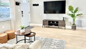 A modern living room with a sofa, coffee table, and a TV mounted on the wall. - Cozy Remodeled House! (Port Richey)