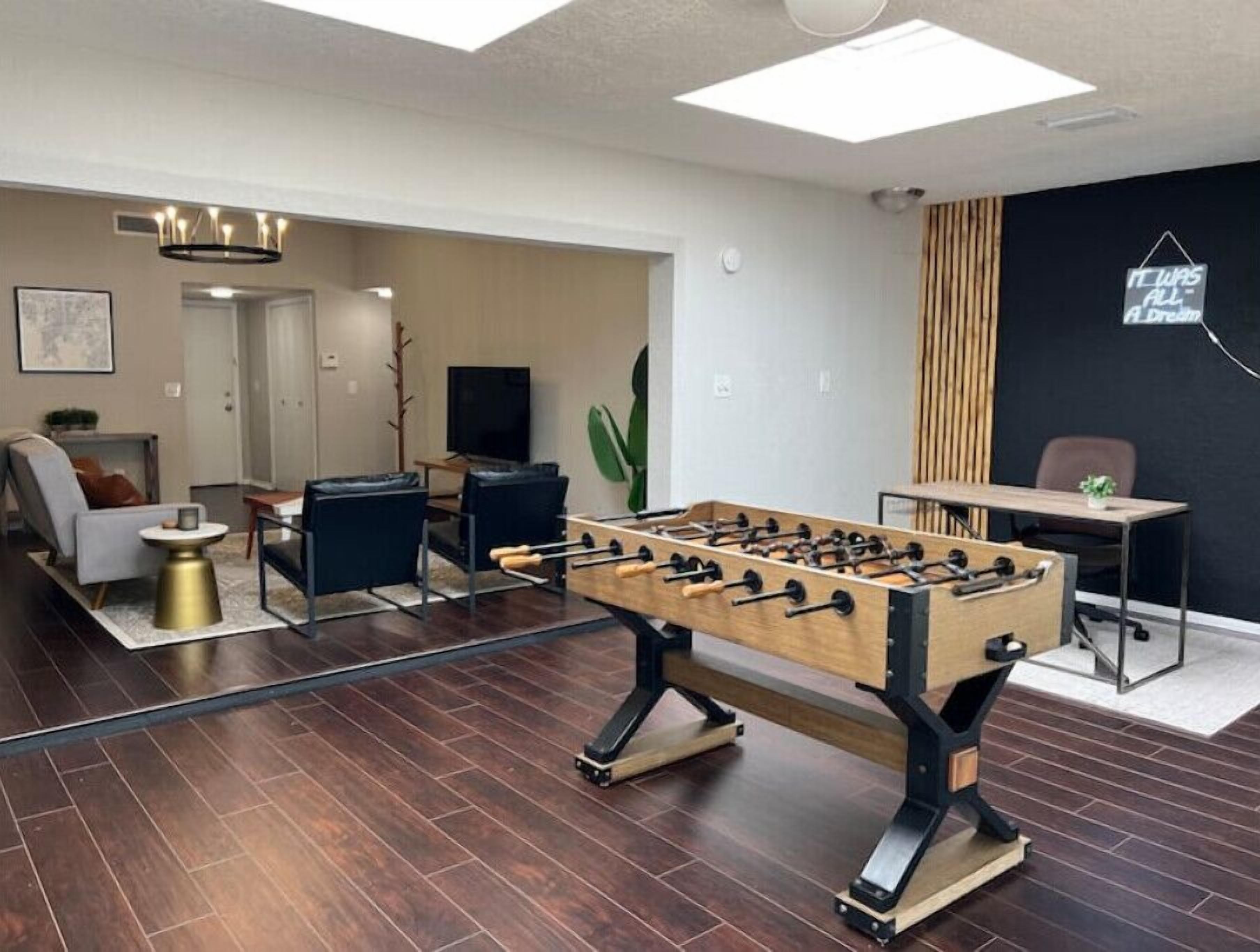 Un salon avec un baby-foot, un canapé, une table basse et un téléviseur.