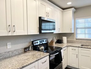 A kitchen with white cabinets, a black stove, and granite countertops.