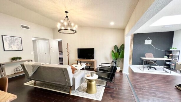 A modern living room with a sofa, TV, and a dining area with a table and chairs.