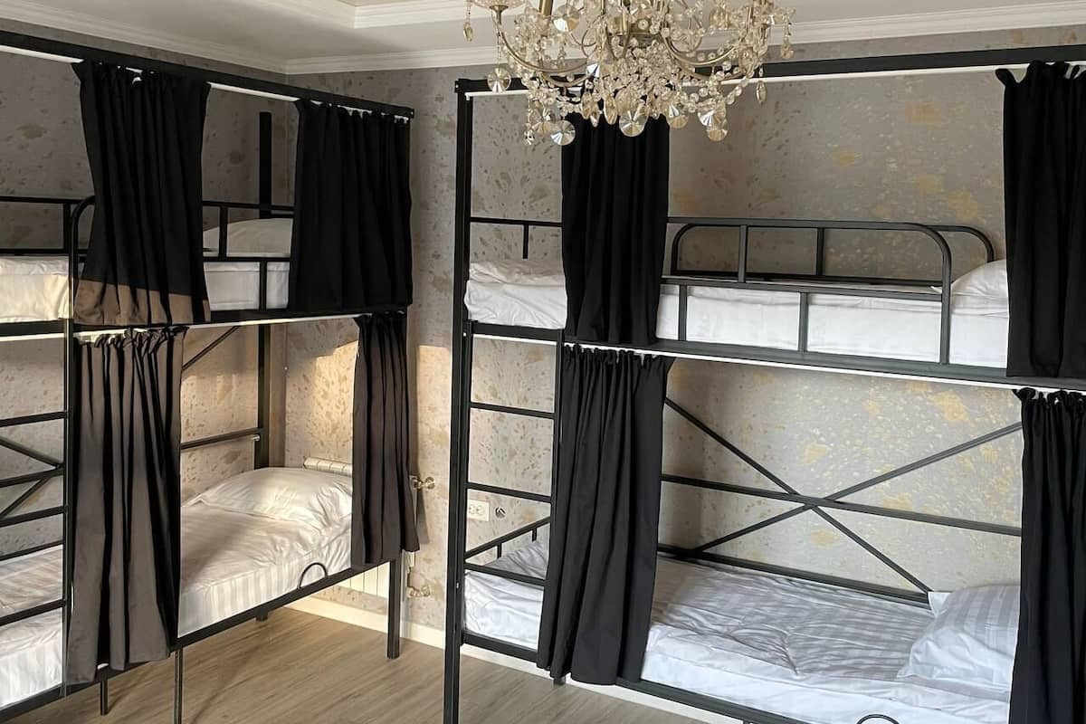 Ein Zimmer mit Etagenbetten, schwarzen Vorhängen und einer Chandelüster.