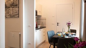 Een kleine keuken met witte kasten, een zwart aanrecht en een ontbijtgedeekte eettafel.