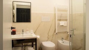 Een moderne badkamer met een douchecabine van glas, een witte wastafel en een toilet.
