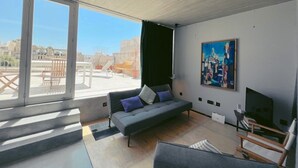 A modern living room with a sofa, a painting, and a TV. - Nobile Apartments  (Valletta)