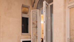 A courtyard with a tiled floor, a glass table, and a door leading to an interior space. - Nobile Apartments  (Valletta)