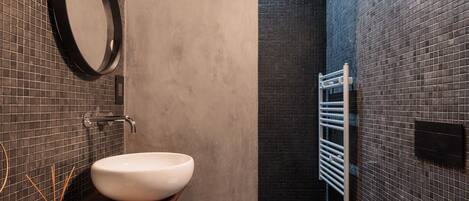 A modern bathroom with a round mirror, a white sink, and a bathtub.