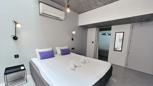 A modern bedroom with a large bed, two bedside tables, an air conditioning unit, and a hanging light fixture. - Nobile Apartments  (Valletta)