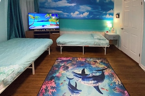 A room with two beds, a TV, a wall mural, and a nightstand with a lamp. - Rochester Escape w/ Hot Tub & Fire Pit! (Rochester)