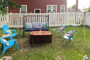 A backyard with a swing set, a fire pit, and outdoor seating. - Rochester Escape w/ Hot Tub & Fire Pit! (Rochester)