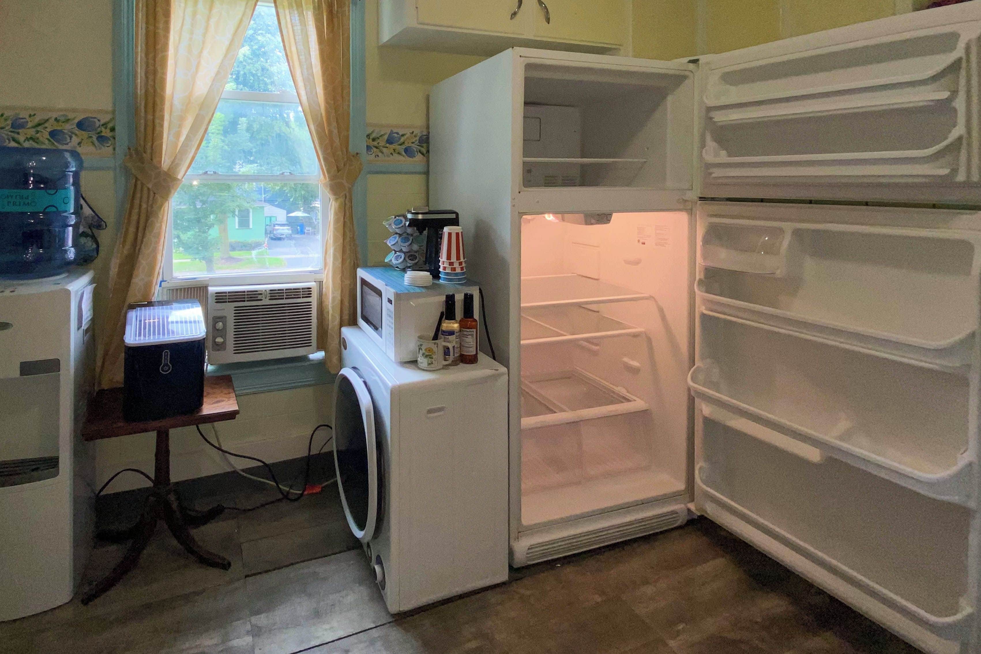 Una cocina compacta con refrigerador, microondas y lavadora.