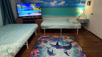 Habitación de hotel con dos camas, televisión, mesita de noche y un mural con una escena de playa.