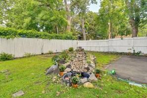 A garden with a water feature, potted plants, and a white picket fence. - Rochester Escape w/ Hot Tub & Fire Pit! (Rochester)
