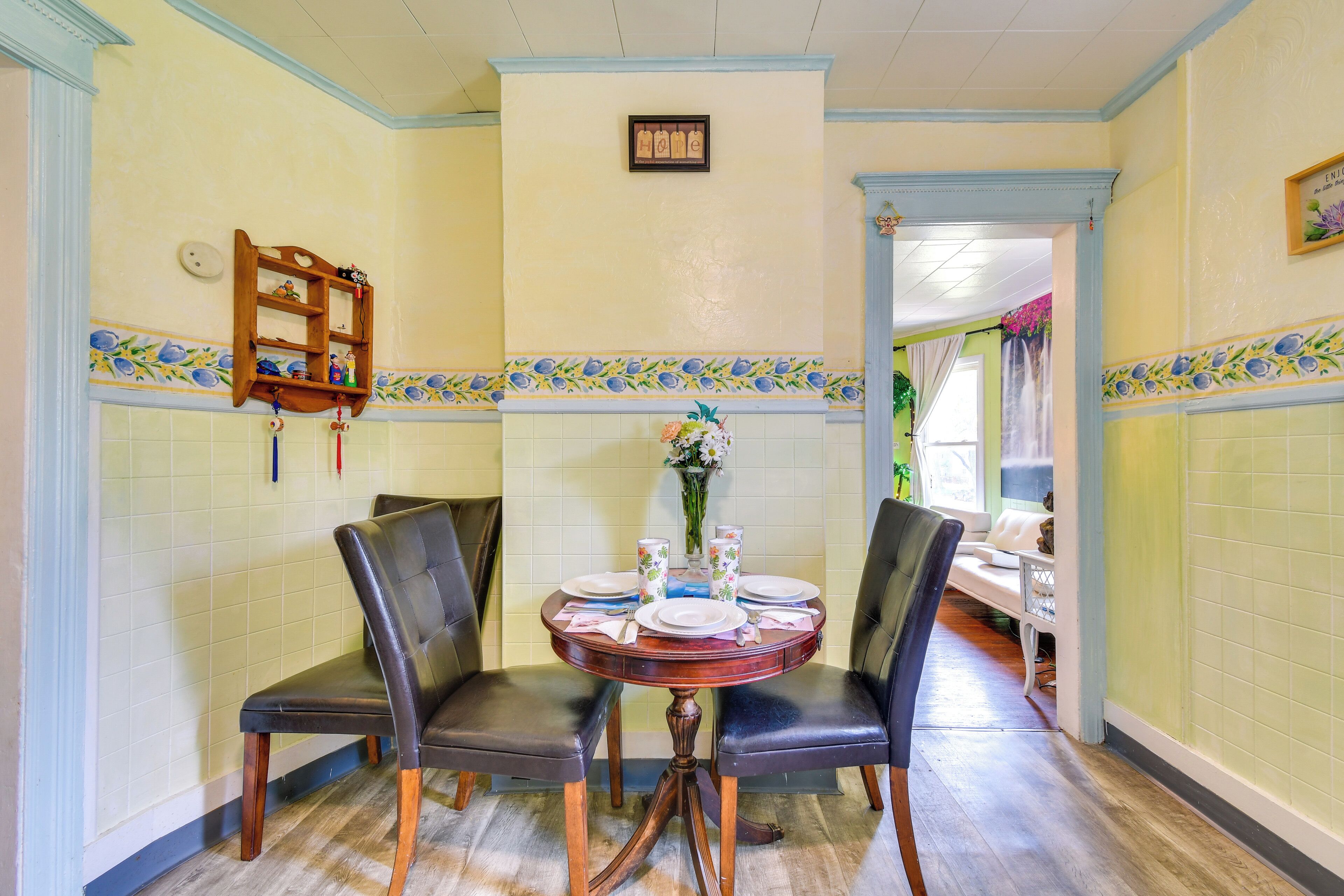 Uma sala de jantar com uma mesa redonda, duas cadeiras e um detalhe decorativo na parede.