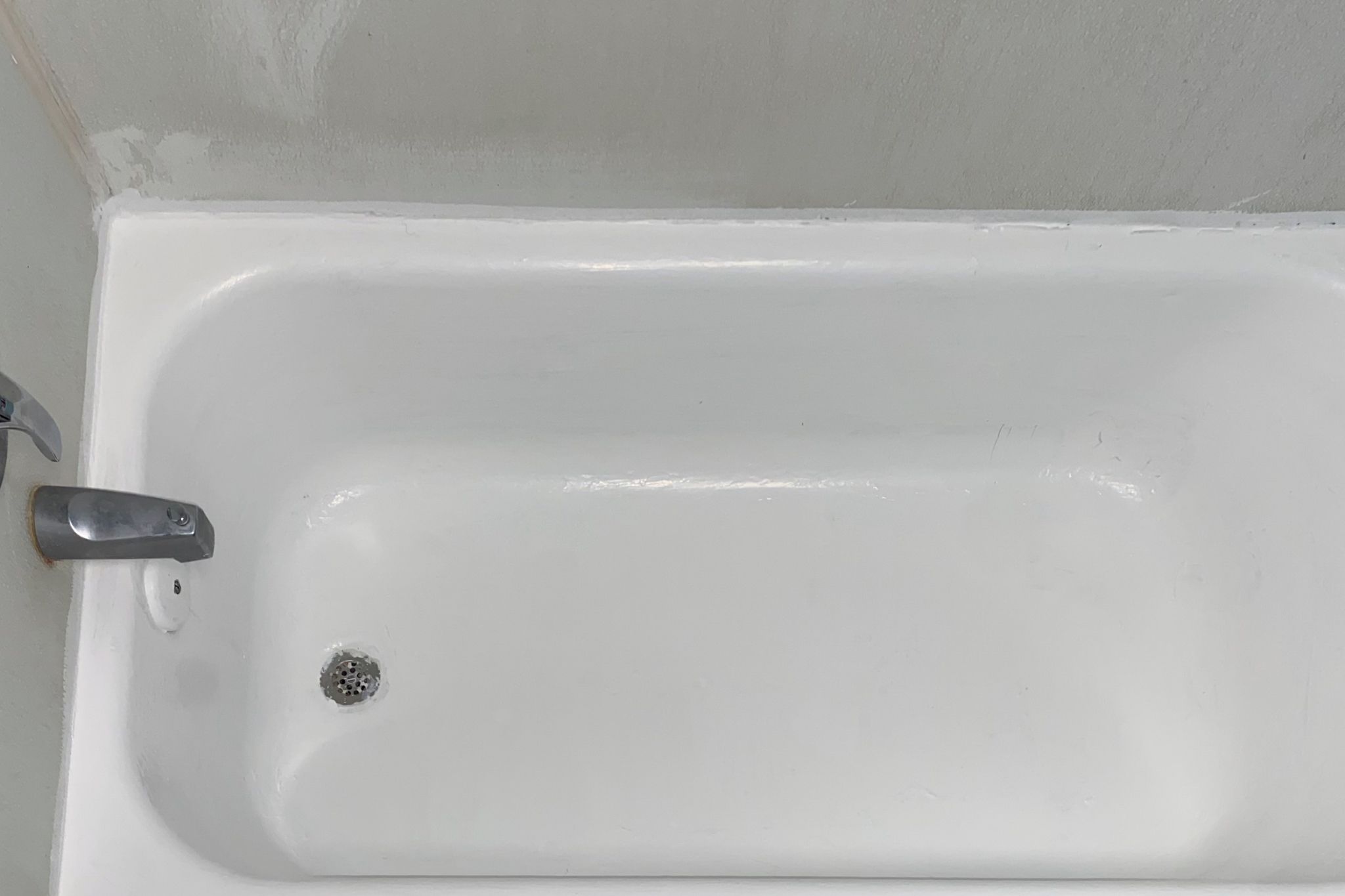 A white bathtub with a faucet and a drain.