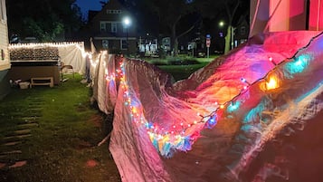 Ein Zelt mit bunten Lichtern und einem weißen Zaun im Garten.