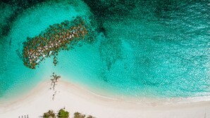 An aerial view of a beach with clear turquoise waters, a sandy shore, and scattered rocks. - Mistral, Ocean view 3BR villa 7 min from beach (Providenciales)
