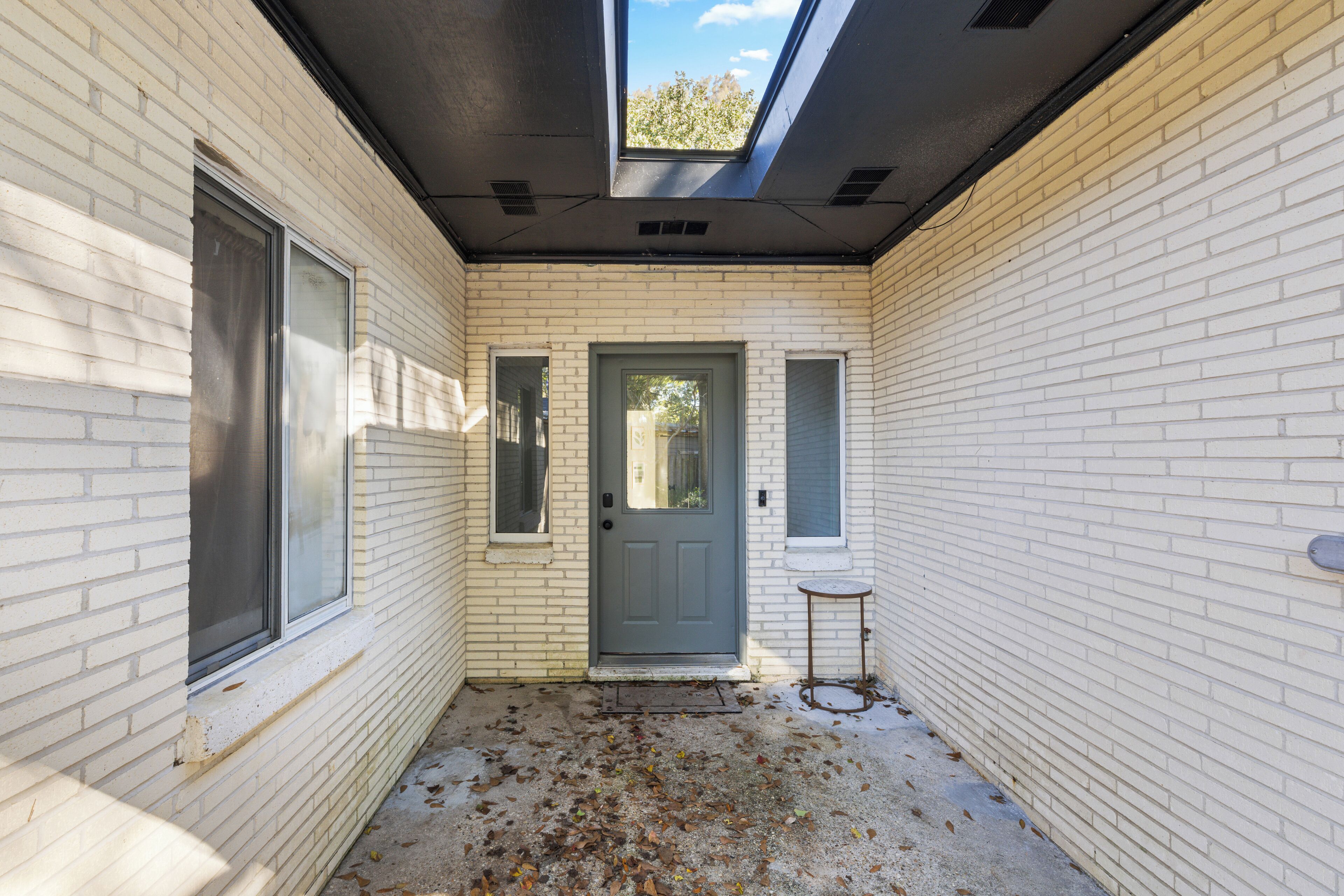 A narrow corridor with a grey door, a small window, and a skylight.